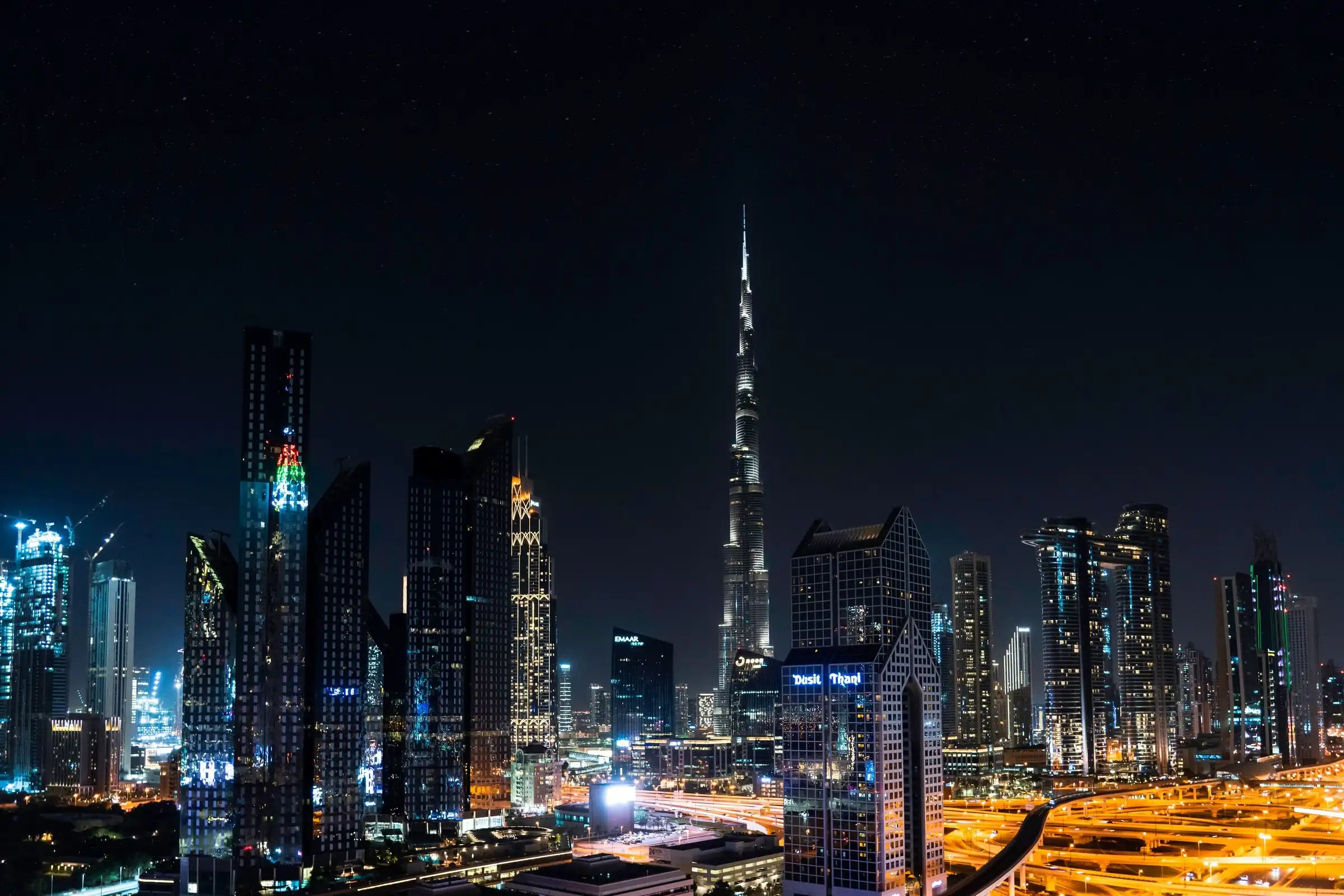 Burj Khalifa rising above the lit towers of Downtown Dubai at night