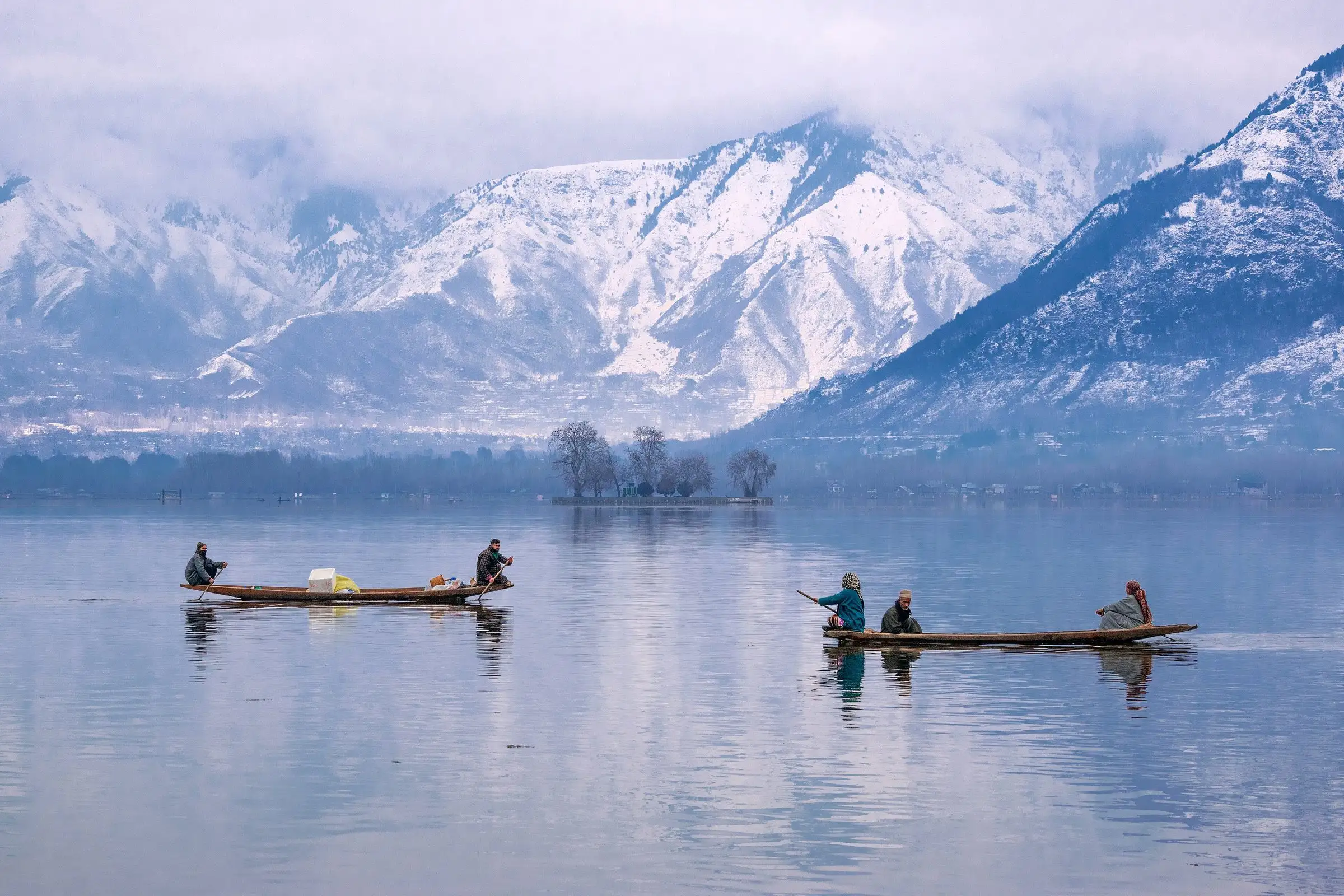 Shikara boats on Dal Lake with snow-covered mountains behind