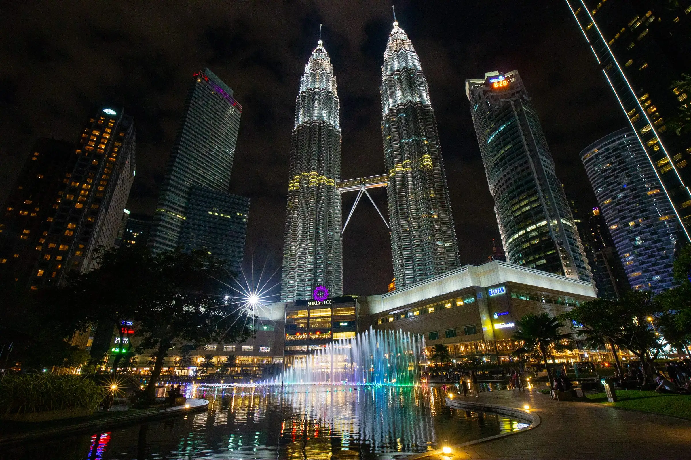 The Petronas Twin Towers lit up at night above a fountain