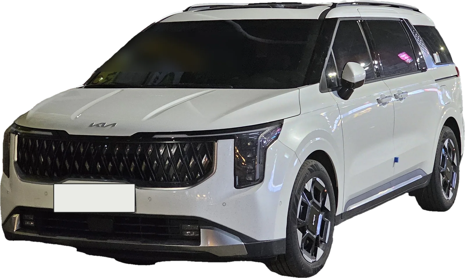 A white Kia Carnival, front three-quarter view